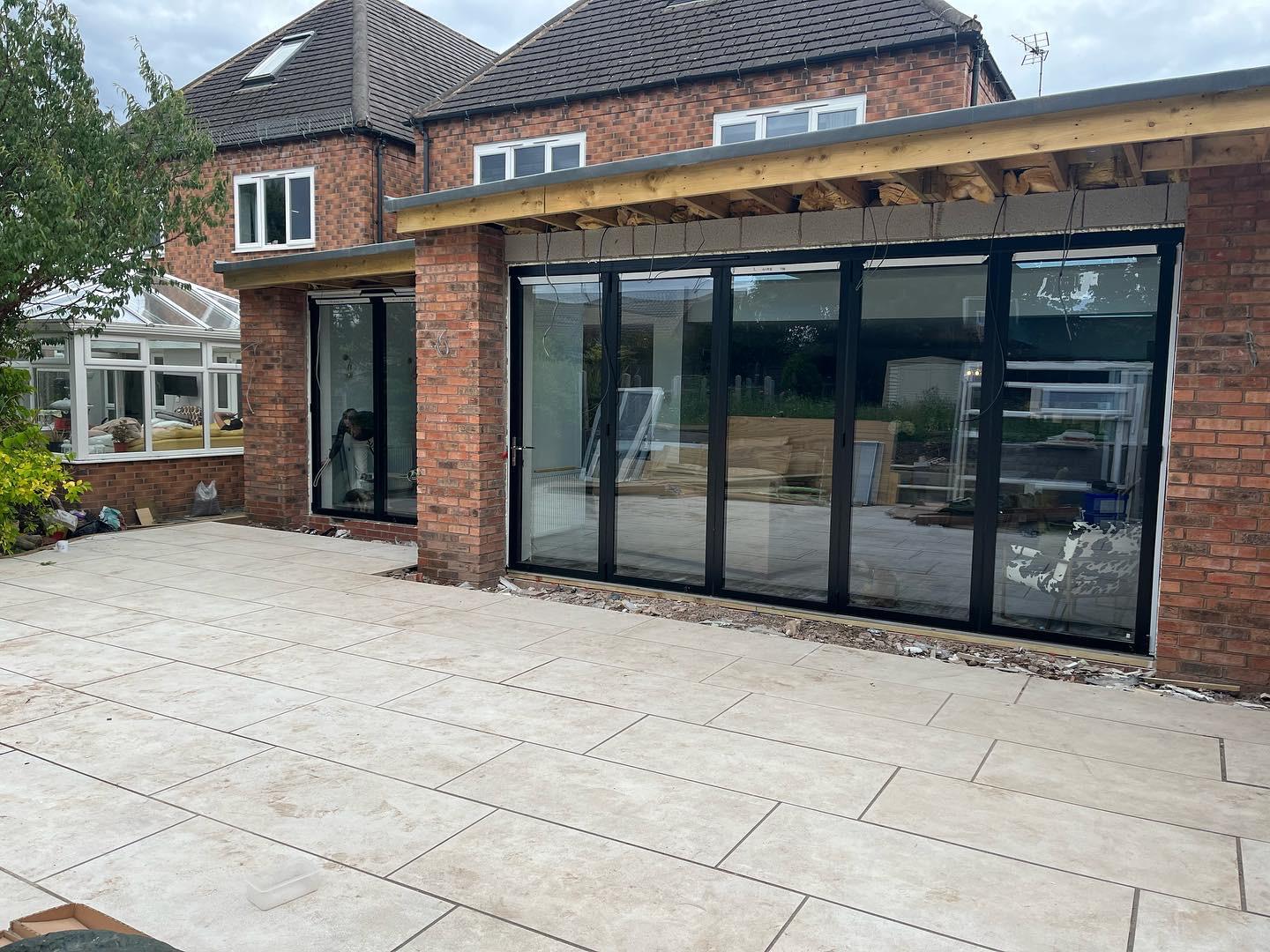Brick house with a newly installed glass extension on a sunny day.