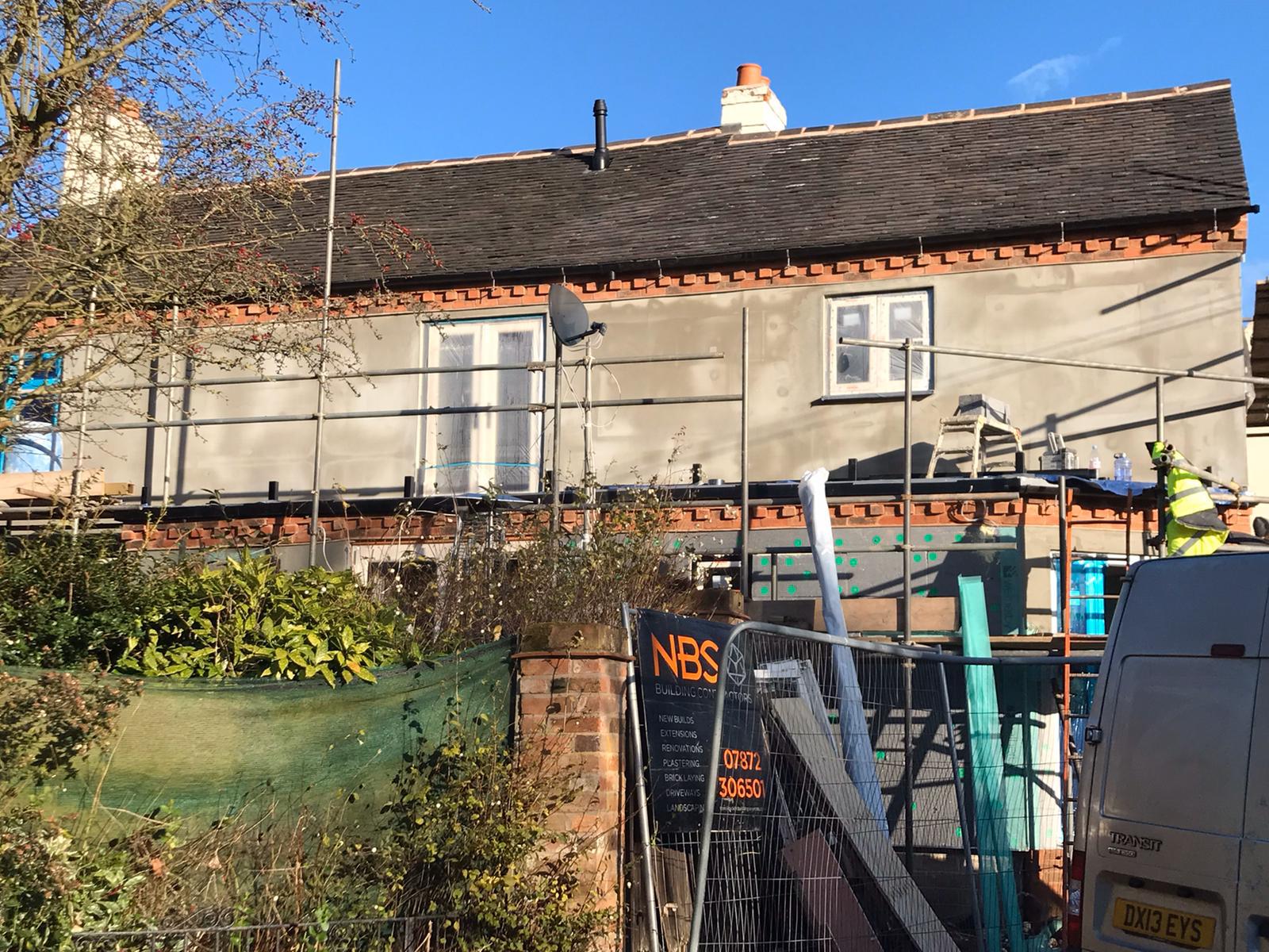 House under renovation with scaffolding and construction materials